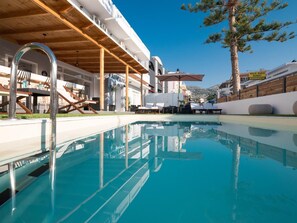Ett poolområde med solstolar och en pergola av trä.