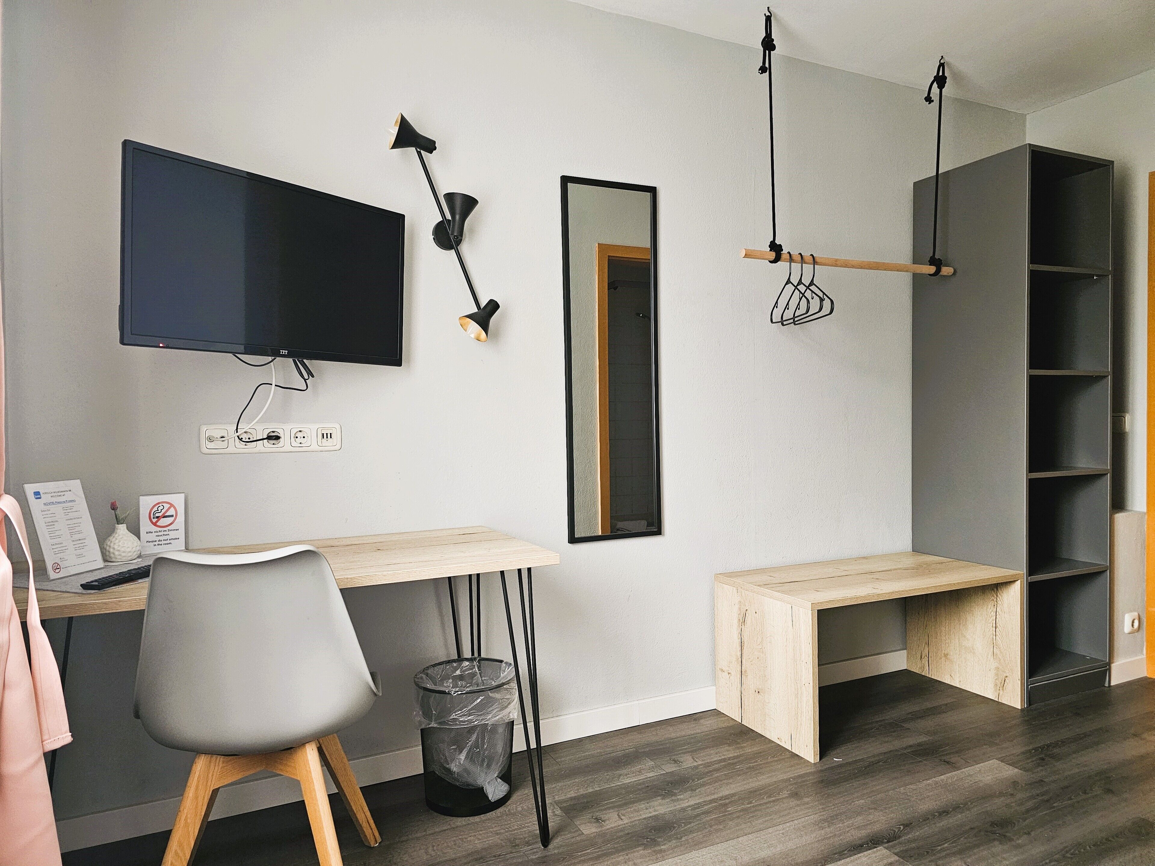 A modern office space with a desk, chair, TV, and shelving unit.