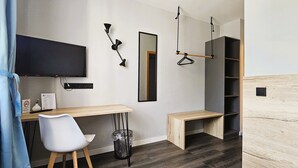 Un dormitorio moderno con escritorio, silla, televisor y estanterías empotradas.