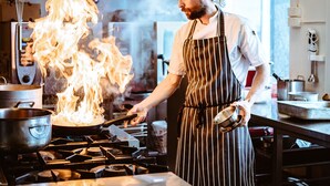 A chef cooking with a large flame on a stove in a professional kitchen. - Venabu Fjellhotell (Ringebu)