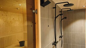 A sauna with wooden walls and a tiled shower area. - Venabu Fjellhotell (Ringebu)