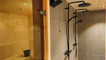 Relax in a serene sauna room with a bench for seating and a shower area.