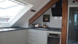 A modern kitchen with a skylight, a built-in oven, and a coffee machine. - Appledore Factory (Bideford)
