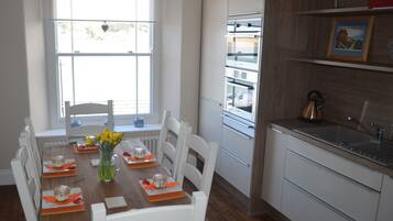 A modern kitchen with white cabinetry, a built-in oven, and a window with a view of the outside.