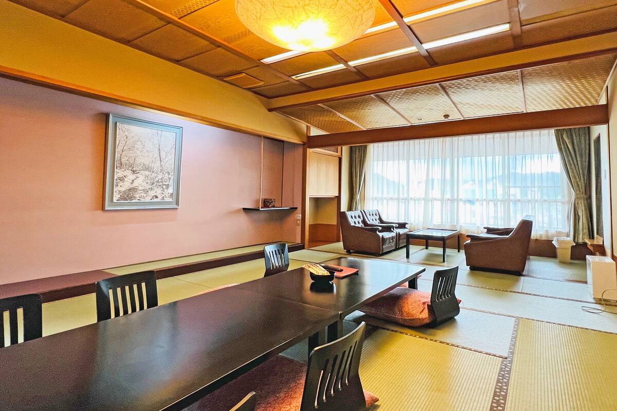 A traditional Japanese-style room with tatami flooring, a low table, and seating arrangements.