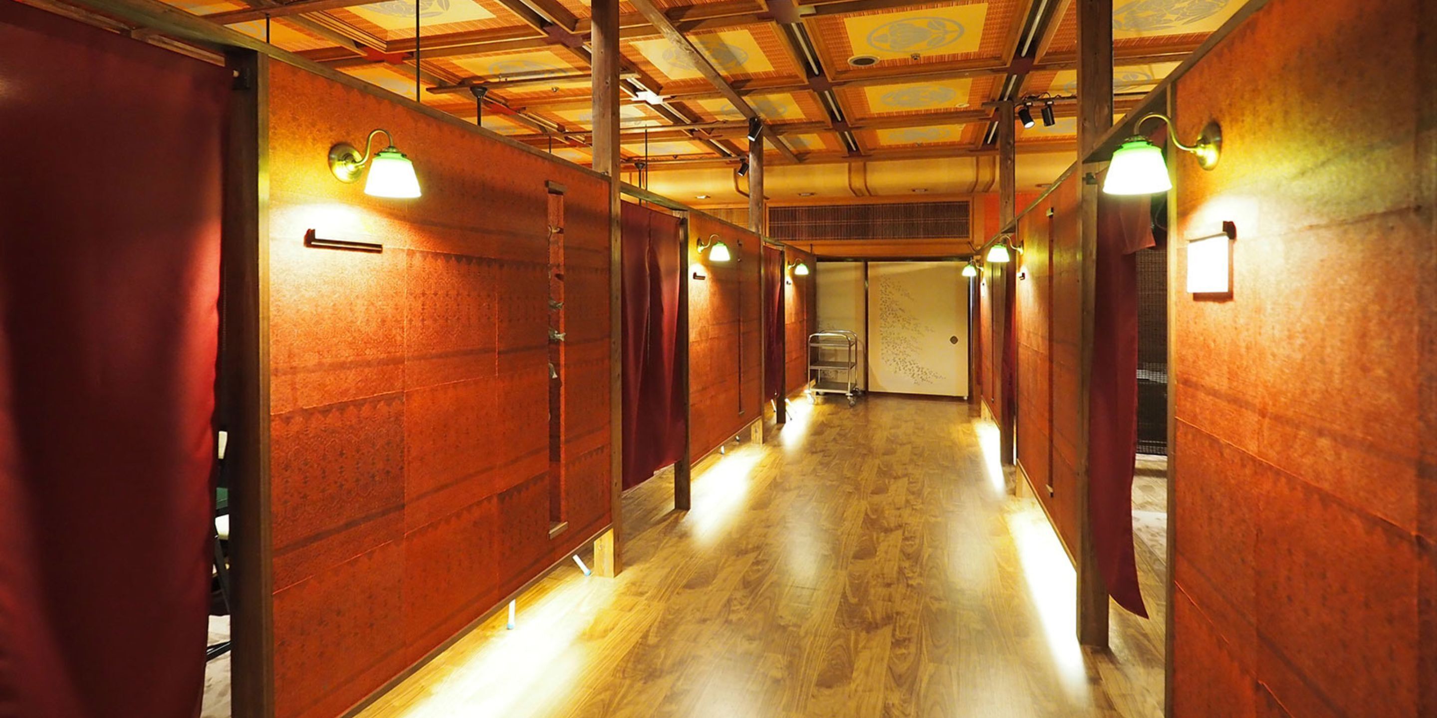 Un couloir aux murs et au sol en bois, équipé de luminaires fixés au mur.