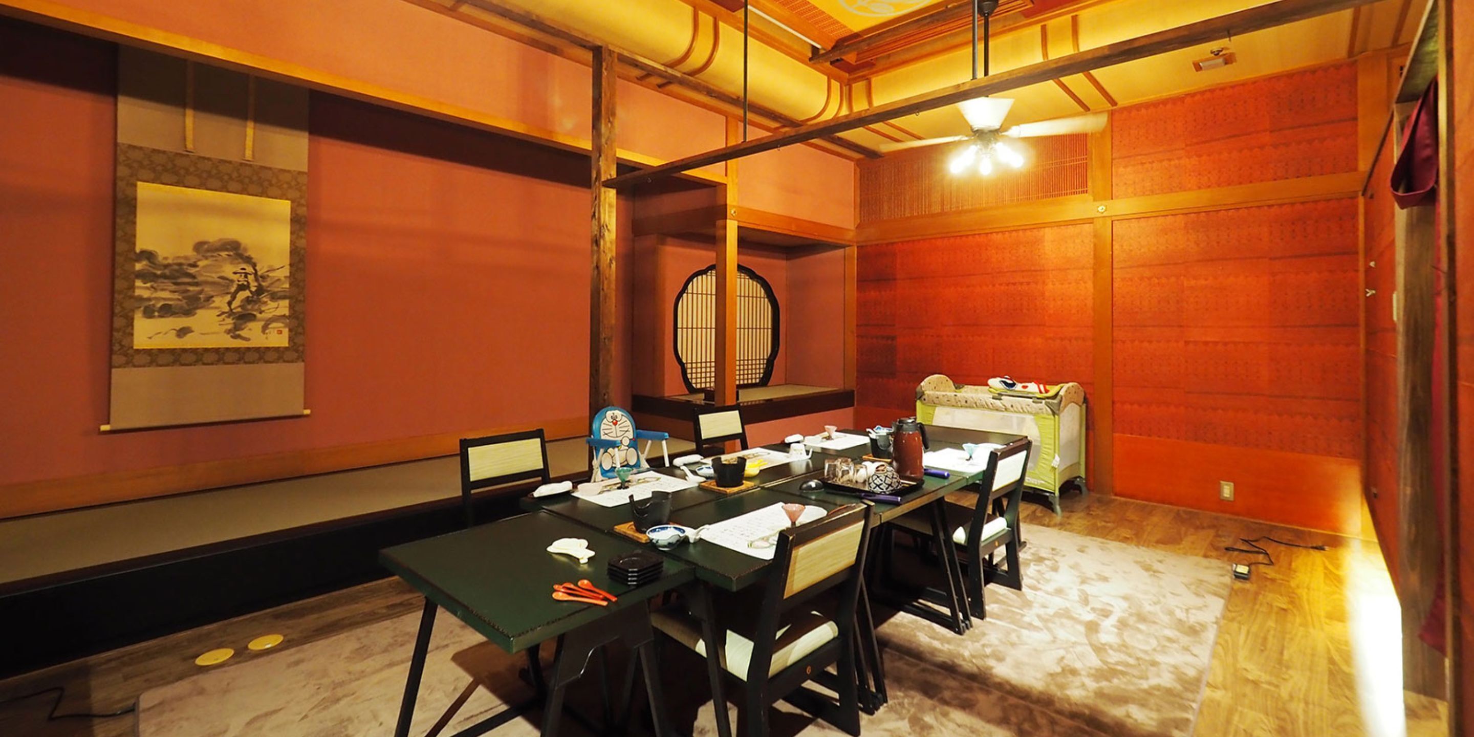 A conference room with a long table, chairs, a traditional Japanese screen, and a ceiling fan.