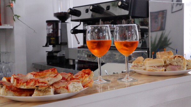 A kitchen counter with a plate of ham and cheese sandwiches, two glasses of orange juice, and a coffee machine in the background. - Hotel Lagomaggio (Rimini)
