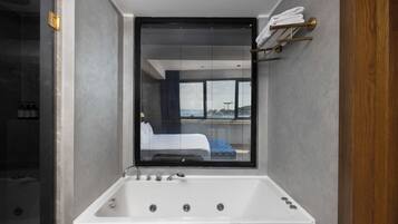 Une salle de bain moderne avec une grande baignoire, une fenêtre avec des stores et un porte-serviettes.