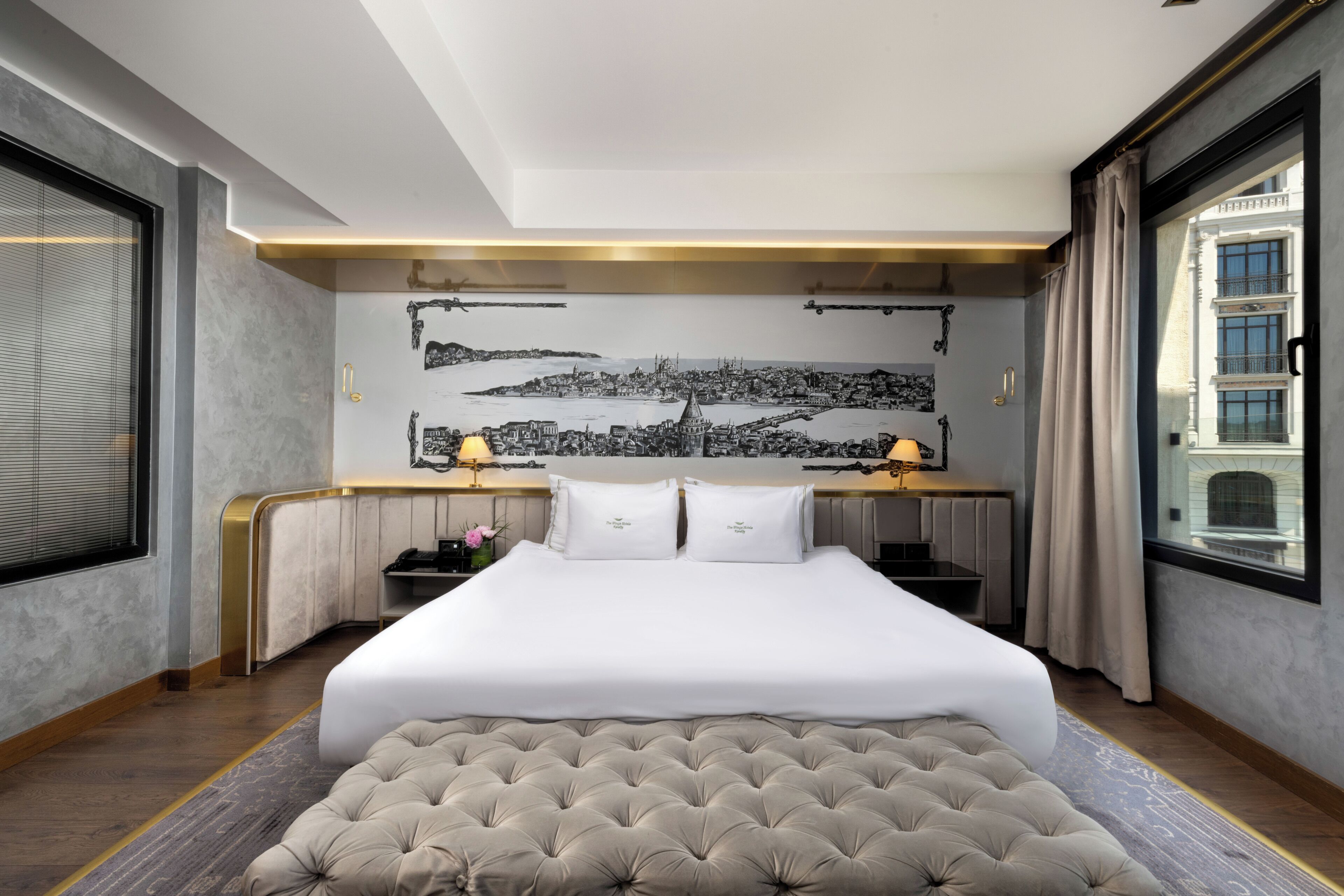Ein Hotelzimmer mit einem großen Bett, einem Schreibtisch und einem Wandgemälde mit Stadtansicht.