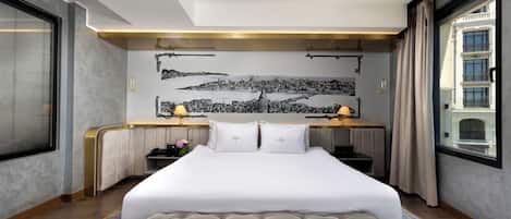 A hotel room with a large bed, a desk, and a cityscape mural on the wall.