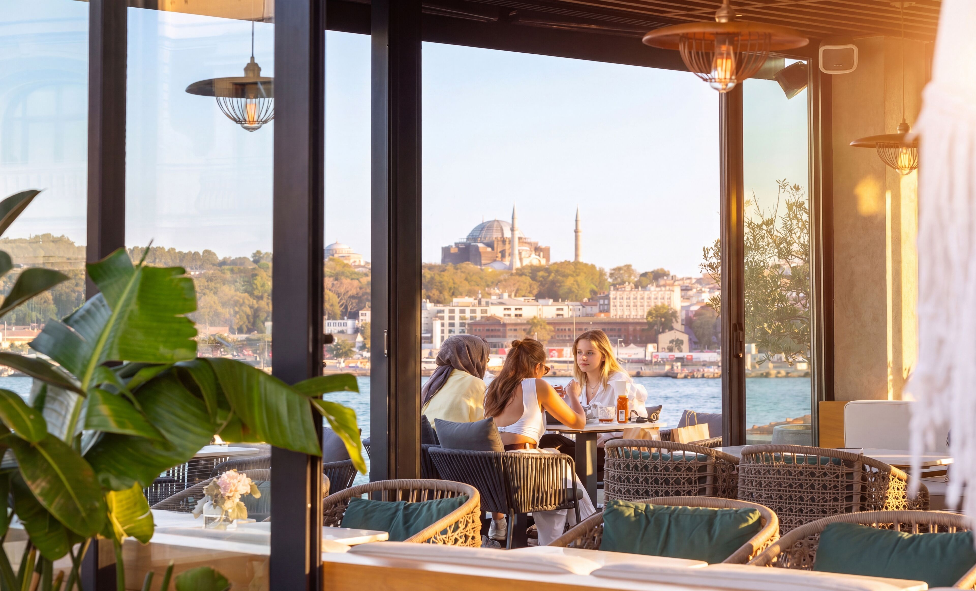 Un restaurant doté d’une terrasse offrant une vue sur la ville, avec un bâtiment remarquable et une étendue d’eau en toile de fond.