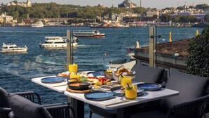 Una mesa lista para el desayuno con vistas a un cuerpo de agua, con barcos y edificios al fondo.