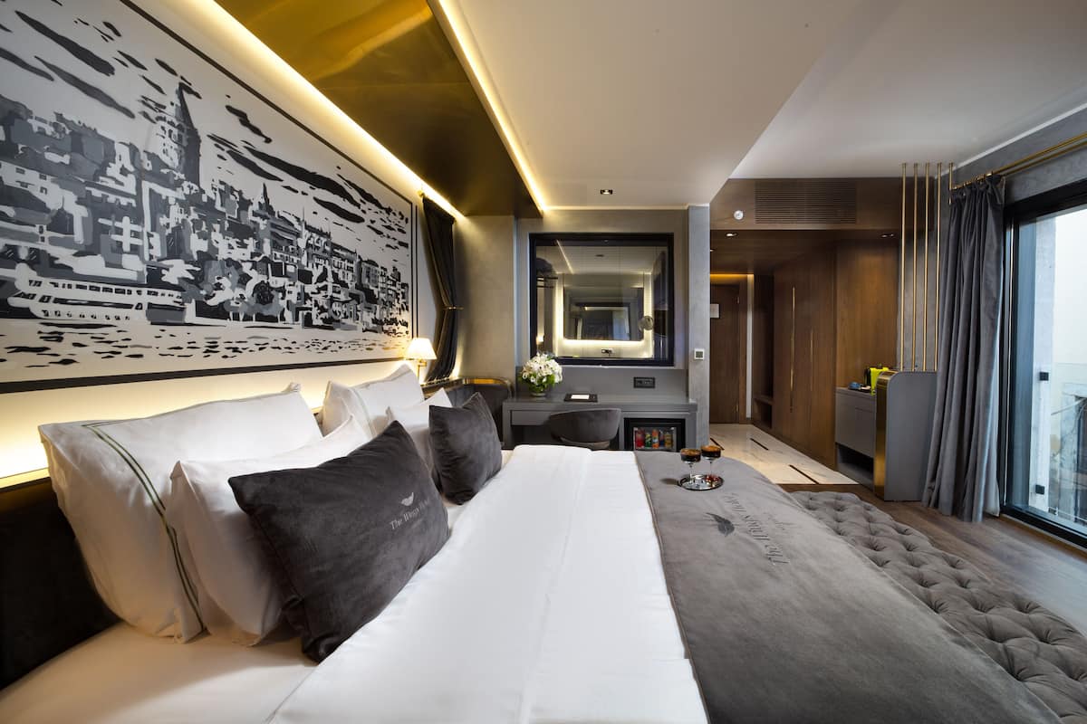 Habitación de hotel moderna con una cama grande, un escritorio, un espejo y vistas a la ciudad.