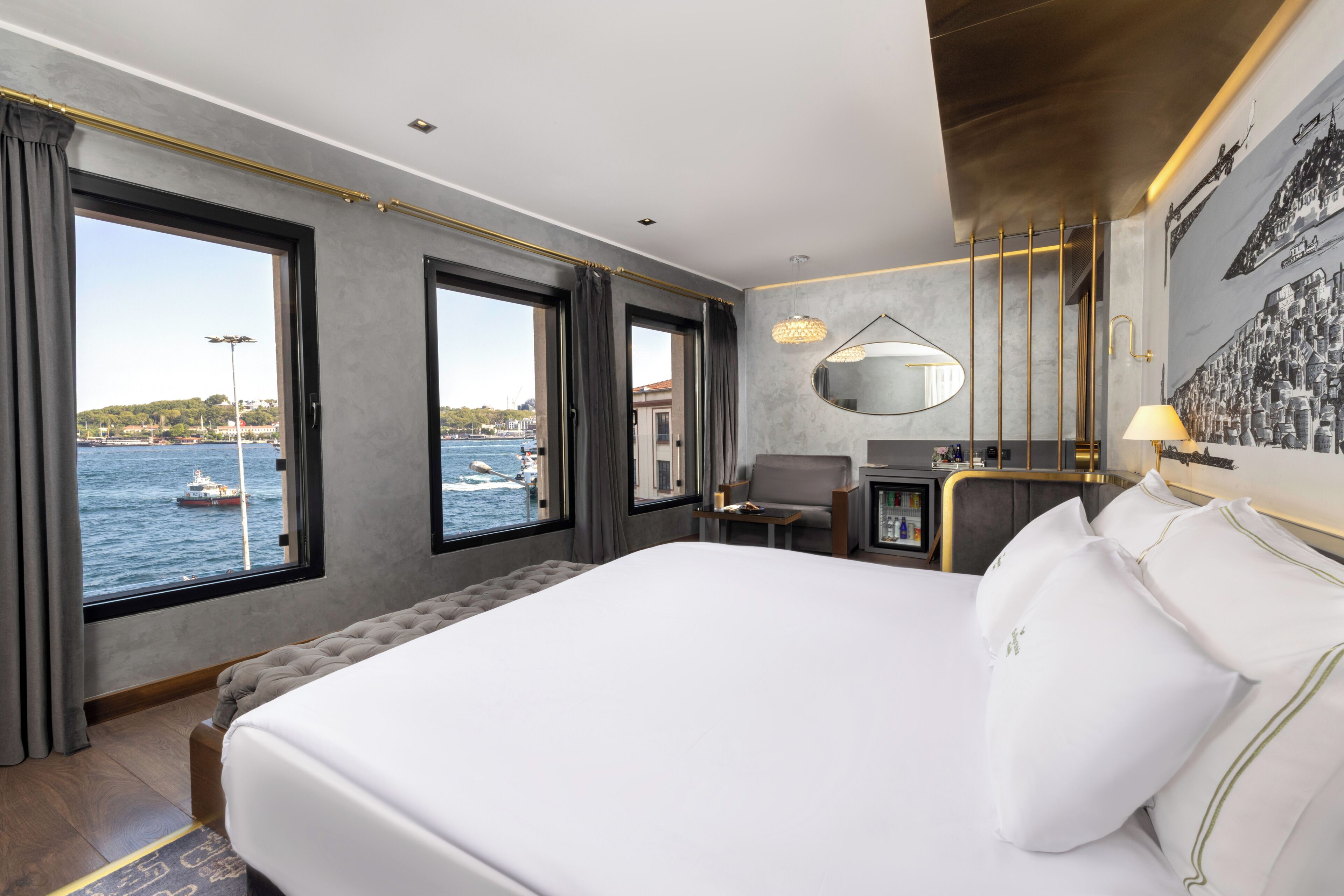 Une chambre d’hôtel avec un grand lit, un bureau, une chaise, un miroir et une vue sur la mer.