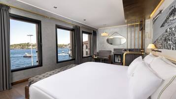 Une chambre d’hôtel avec un grand lit, un bureau, une chaise, un miroir et une vue sur la mer.