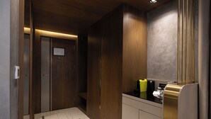 Un baño moderno con muebles de madera, encimera negra y espejo con detalles dorados verticales.