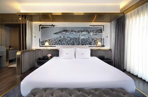 A hotel room with a large bed, two bedside lamps, a nightstand, a desk with a telephone, and a large wall mural. - The Wings Hotels Karakoy (Istanbul)