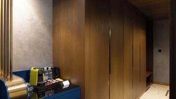 A hotel room with a minibar, wooden wardrobe, and a tiled floor.