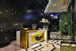 A reception area with a modern design, featuring a marble reception desk, a black and gold color scheme, and a patterned floor. - The Wings Hotels Karakoy (Istanbul)