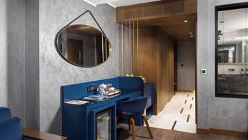 Una habitació d'hotel moderna amb una taula, cadires, un mirall rodó i vista a la ciutat per la finestra.