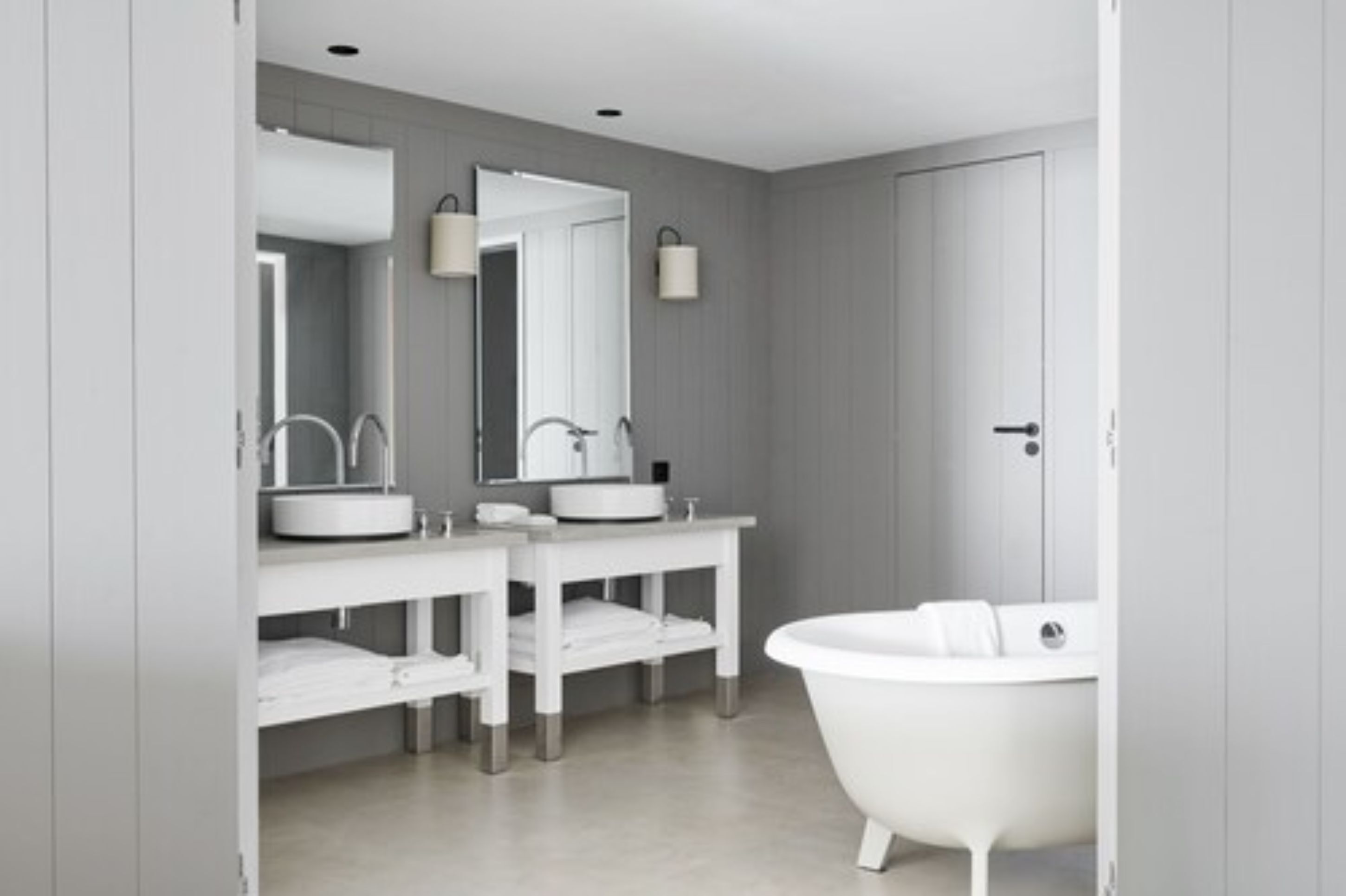 Une salle de bain moderne avec une baignoire blanche, deux lavabos et un grand miroir.