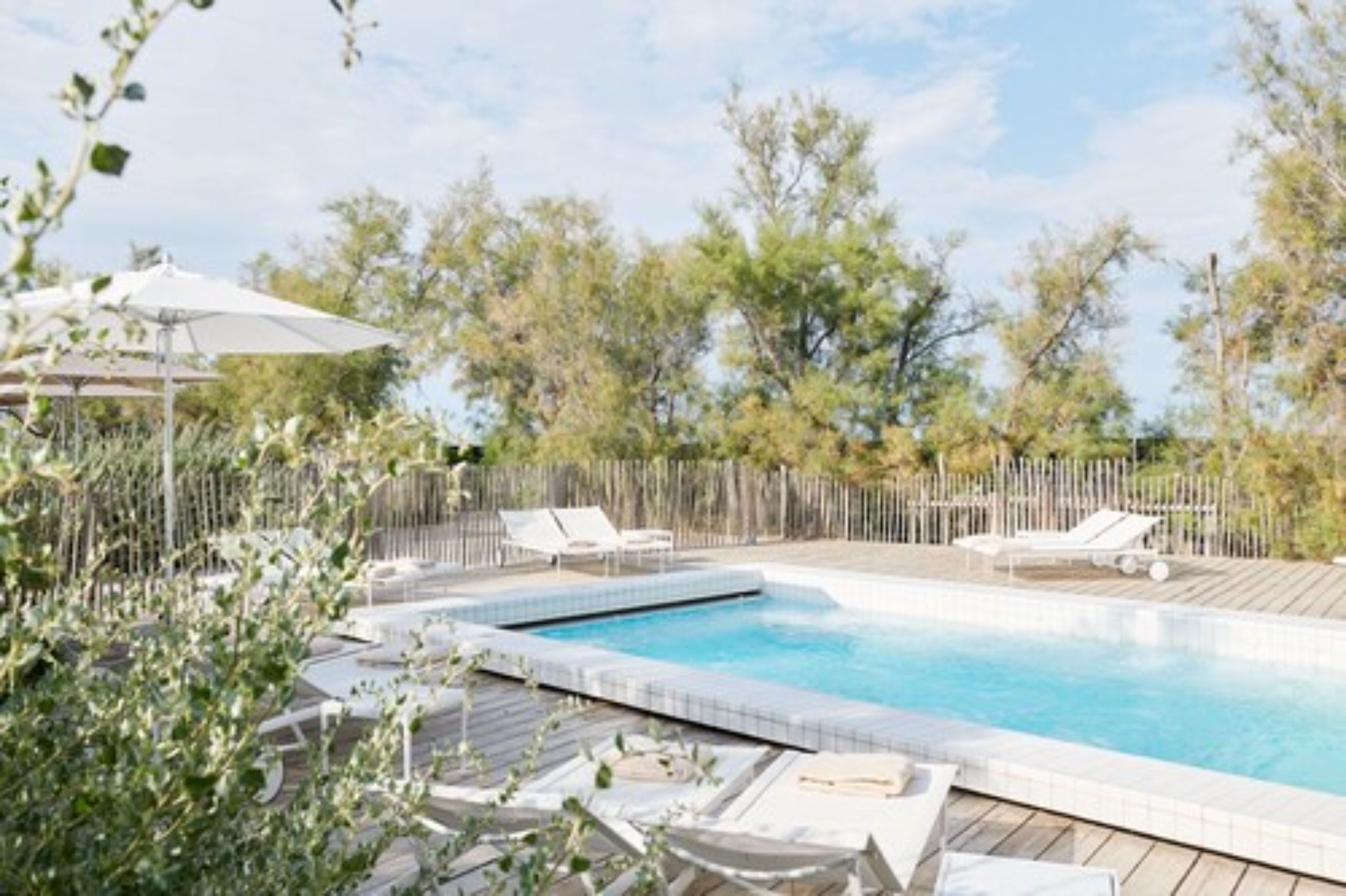 A swimming pool with lounge chairs and a wooden deck.