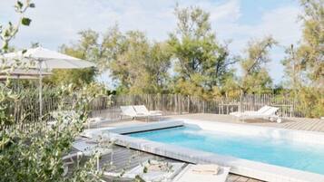 A swimming pool with lounge chairs and a wooden deck.