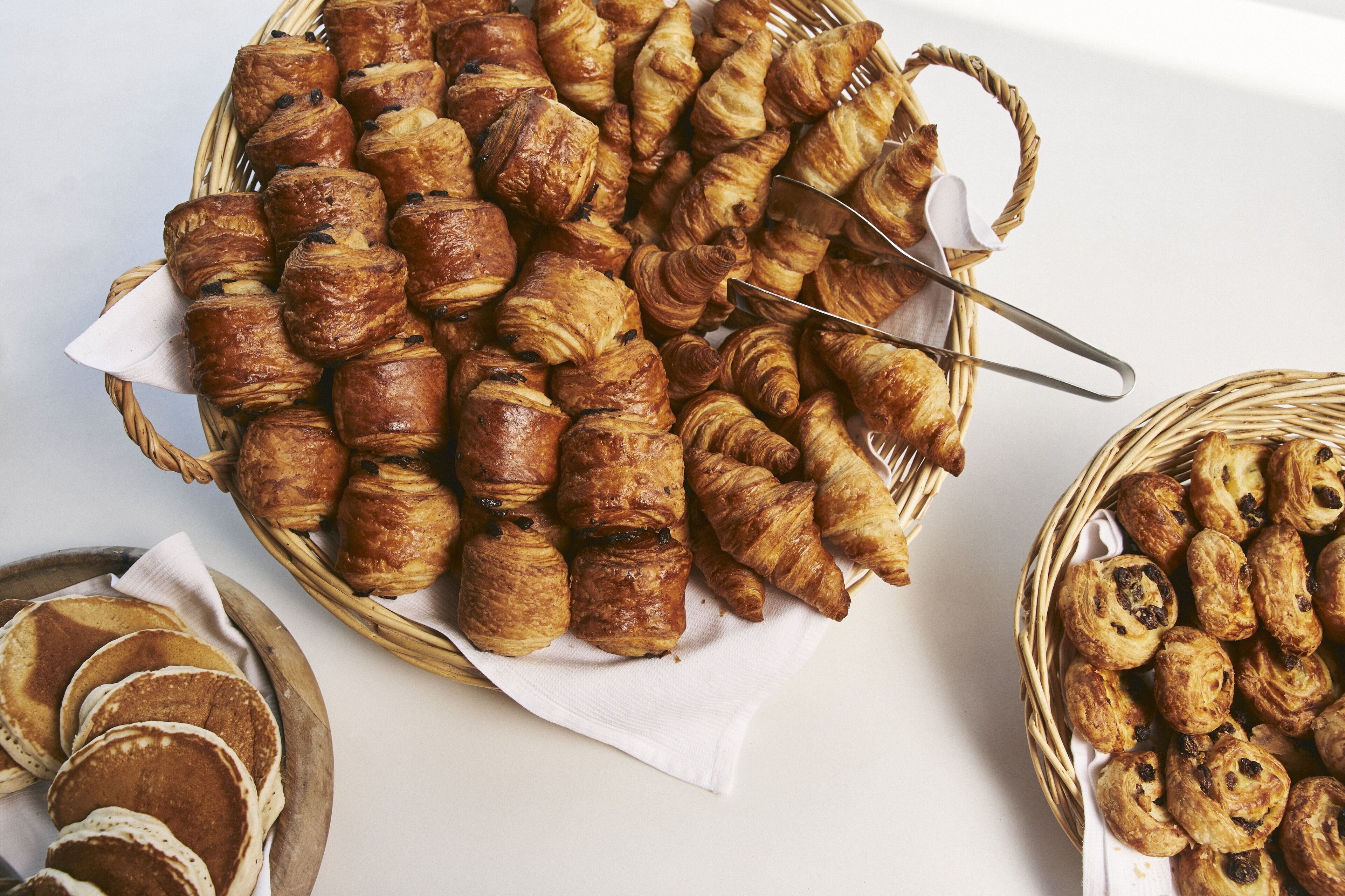 Variedad de pastelería, incluyendo cruasanes y muffins, dispuesta sobre una mesa.