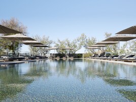 Una piscina al aire libre, sombrillas, sillones reclinables de piscina