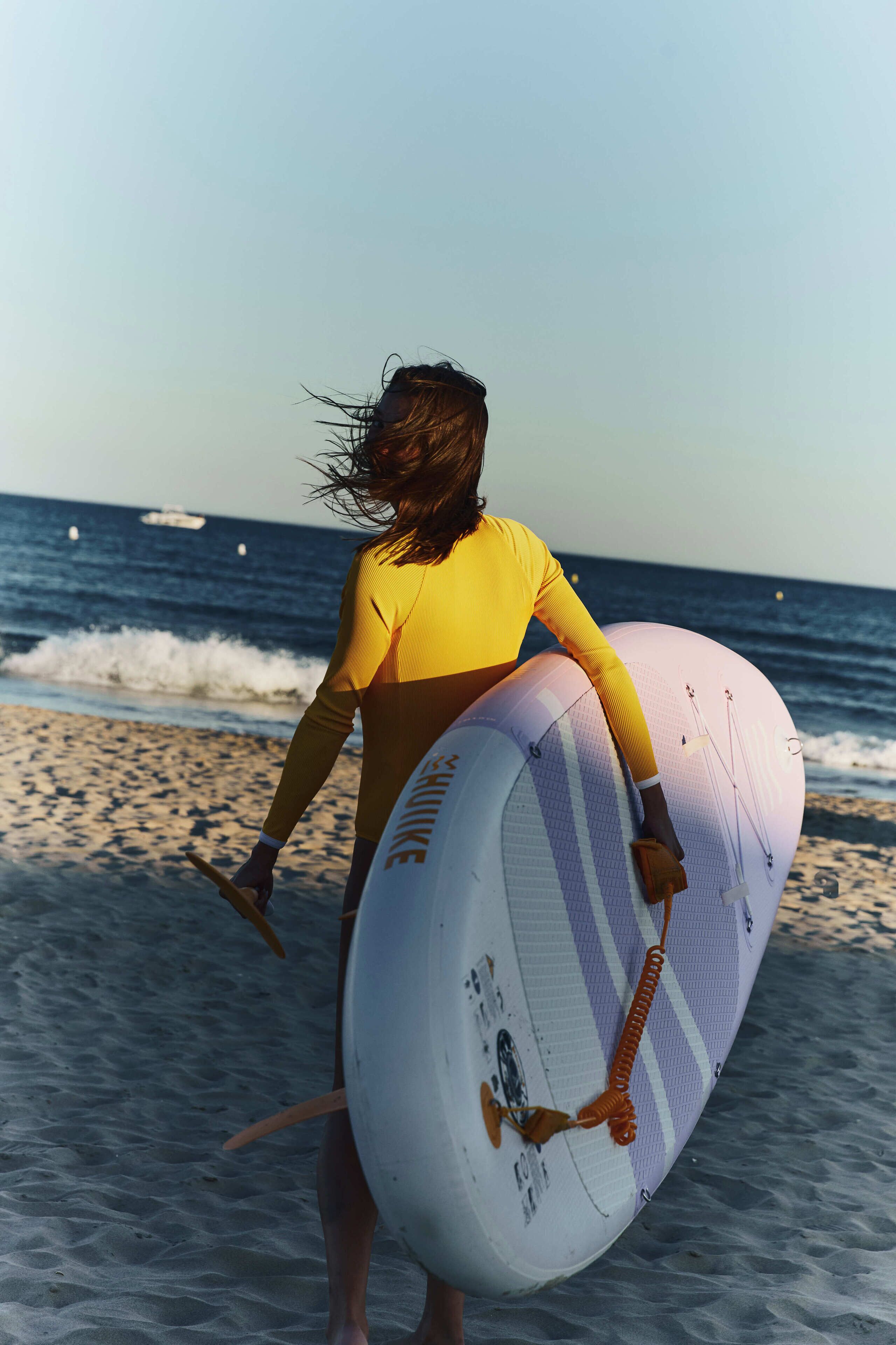A person carrying a surfboard on a beach.