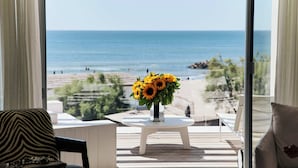 A balcony with a white table and a vase of sunflowers, overlooking a beach and ocean. - Hôtel Plage Palace & Spa (Palavas-les-Flots)