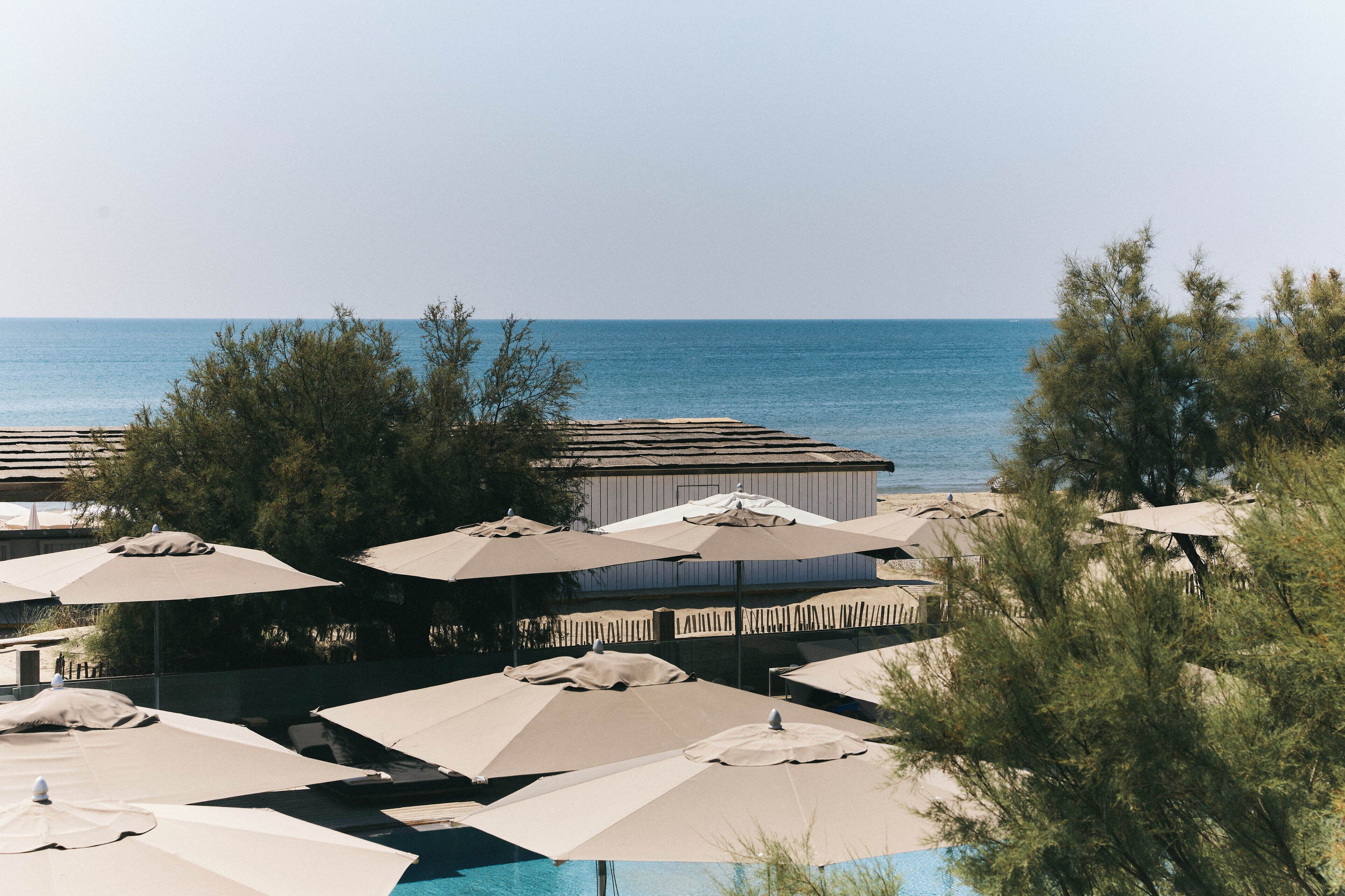 A beachside resort with multiple umbrellas and a pool.