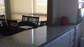 A kitchen with granite countertops, white cabinets, and a dining area with chairs.