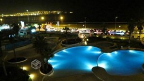 A nighttime view of a swimming pool area with a view of the city skyline in the background.