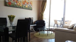 A modern living room with a glass dining table, black chairs, a sofa, and a painting of tulips on the wall. - Departamento Los Lucumos de La Serena (La Serena)