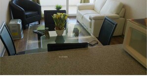 A living room with a glass coffee table, a white sofa, a black armchair, and a small plant. - Departamento Los Lucumos de La Serena (La Serena)