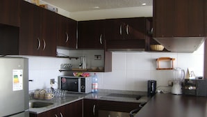 Eine Küche mit dunklen Holzschränken, einem Kühlschrank, einer Mikrowelle, einem Toaster und einem Mixer.