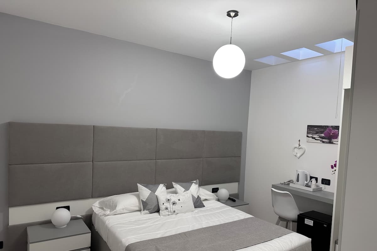 Une chambre à coucher moderne avec un lit, des tables de chevet, un bureau et une chaise.