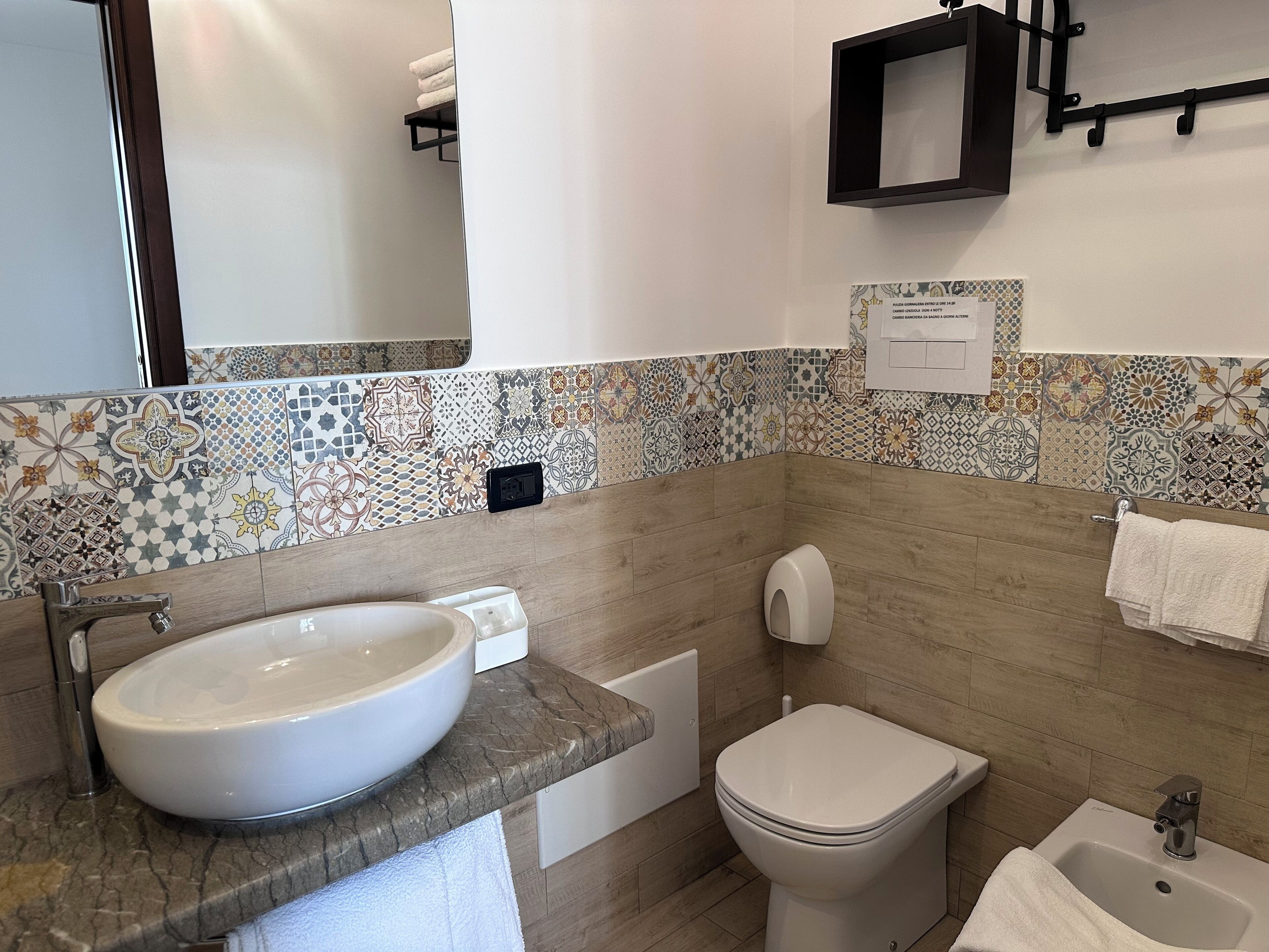 Une salle de bain avec un grand lavabo, des toilettes, un bidet et un miroir.
