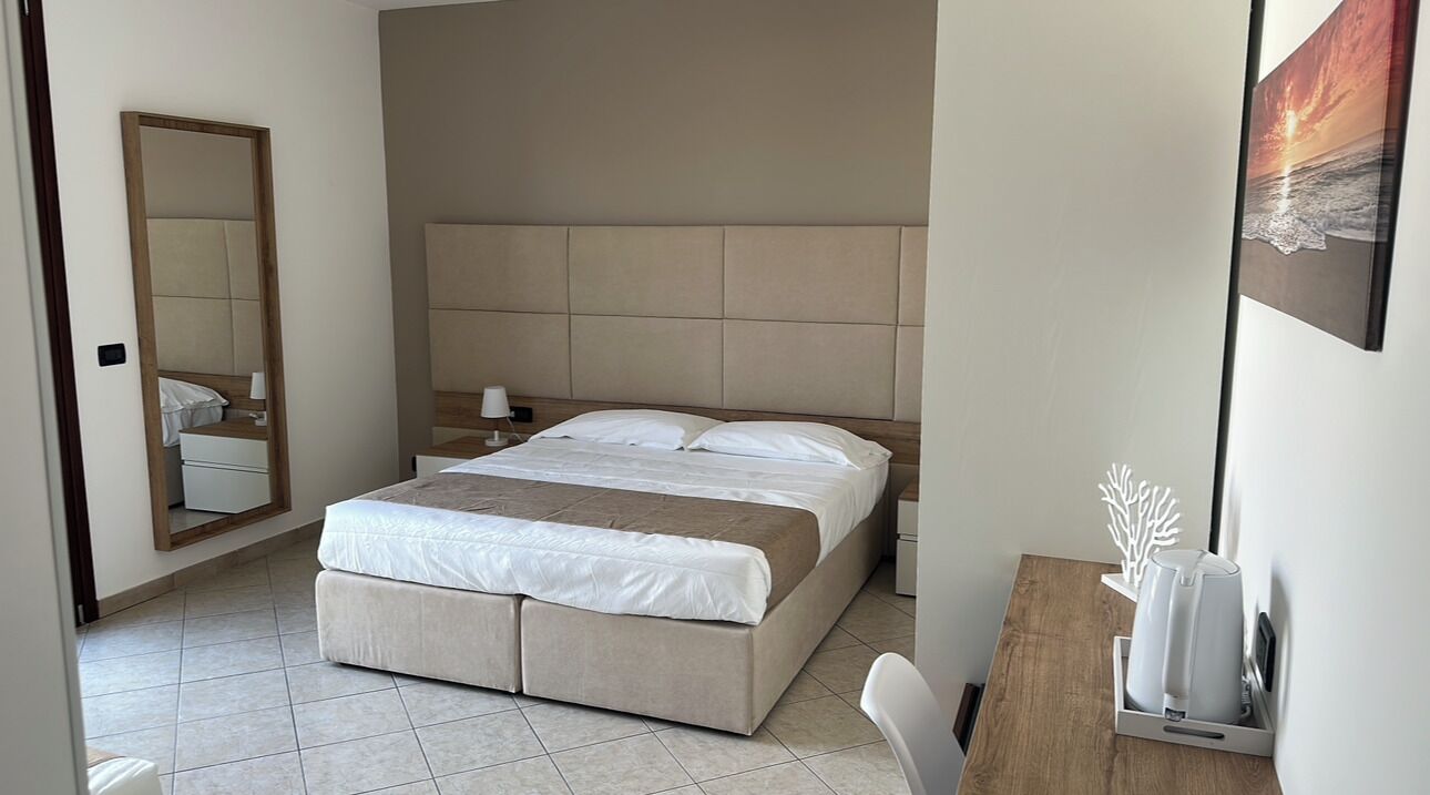 Un dormitorio moderno con una cama grande, una mesita de noche, un espejo y un cuadro en la pared.