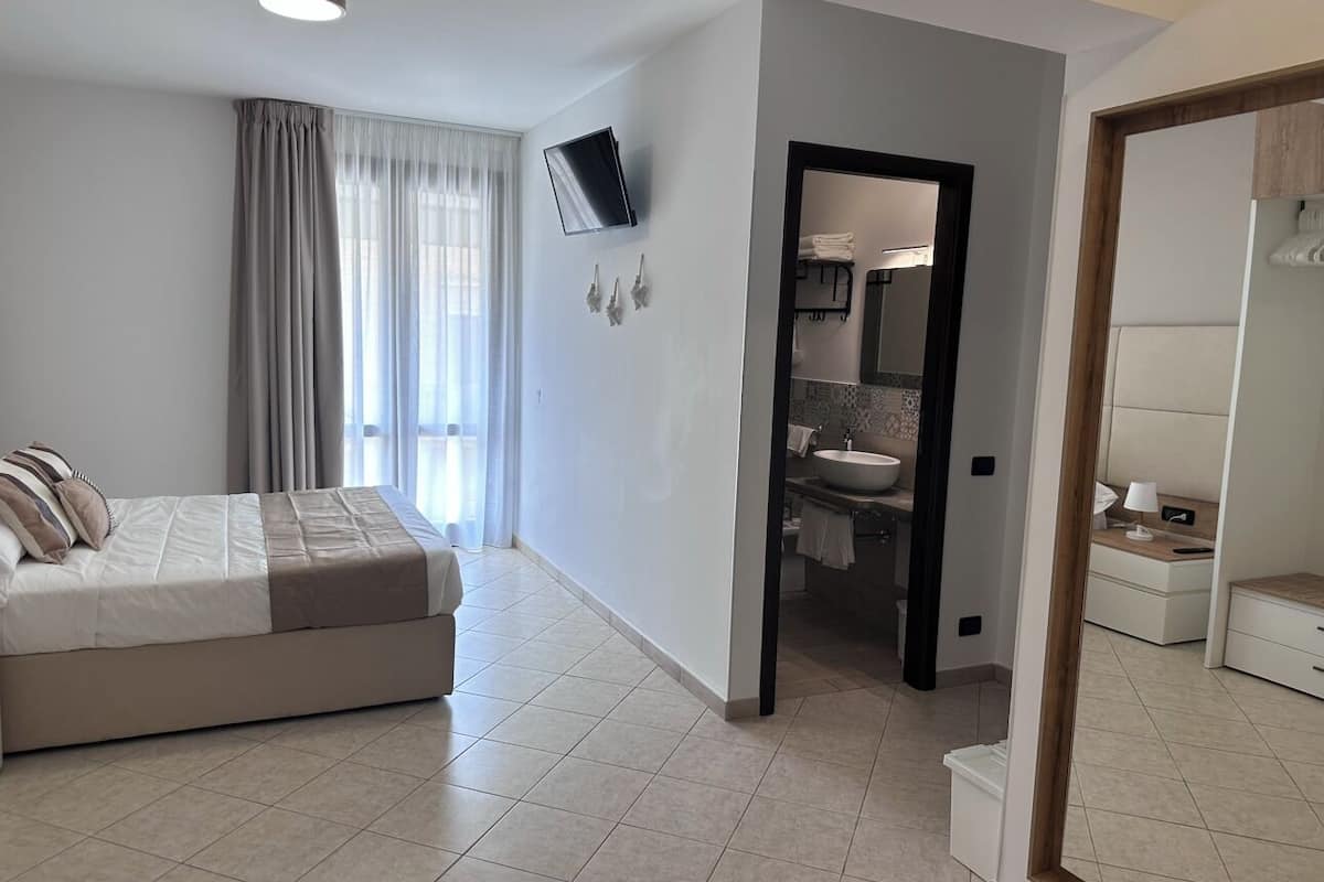 Une chambre d’hôtel moderne équipée d’un lit, d’une salle de bain et d’un téléviseur fixé au mur.