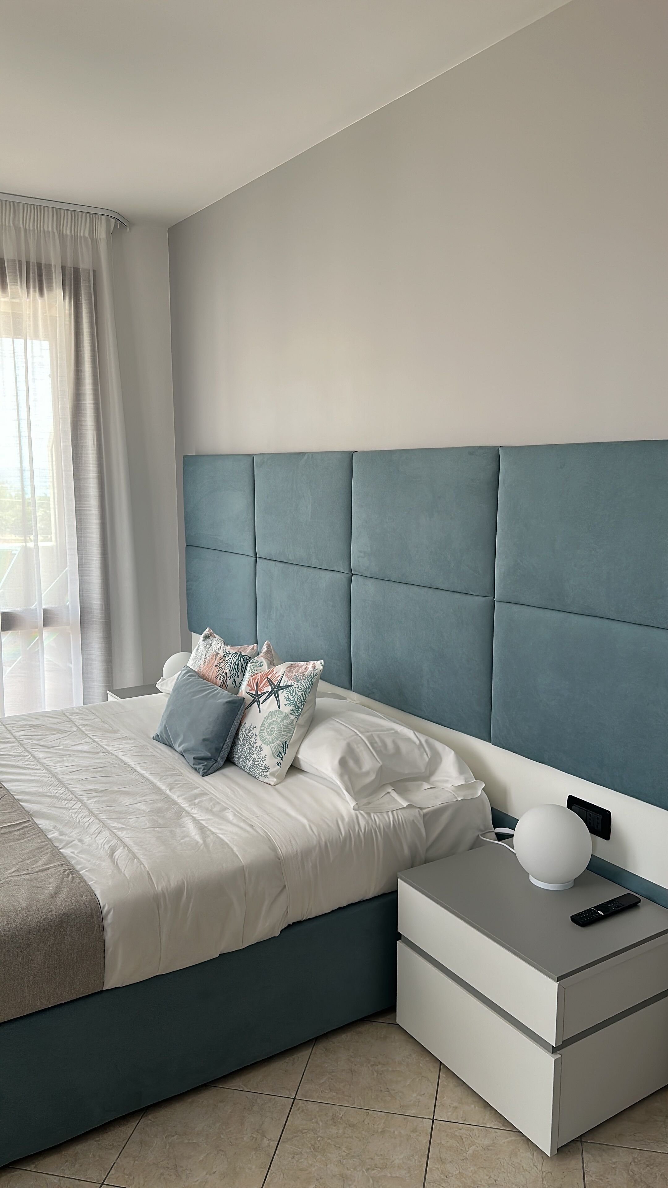 Een moderne slaapkamer met een bed, nachtkastjes en een nachttafeltje.