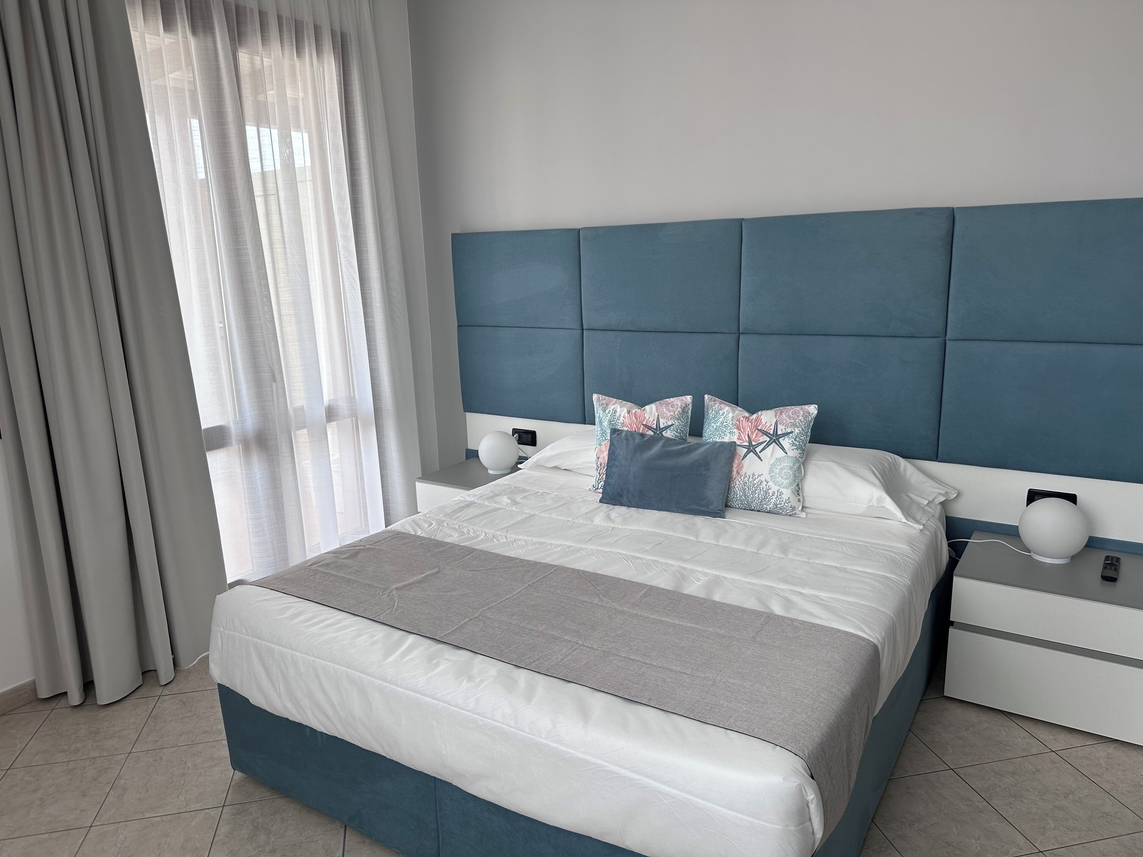 A modern bedroom with a bed, nightstands, and a headboard.