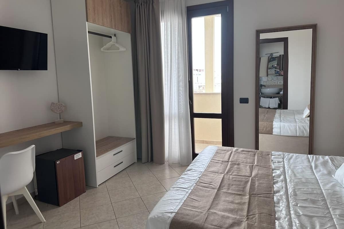Une chambre d’hôtel comprenant un lit, un bureau, une chaise, une armoire et un téléviseur.