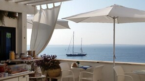 A terrace with white chairs and a table, overlooking the sea with a sailboat in the distance. - B&B Punta Cutieri (Gallipoli)