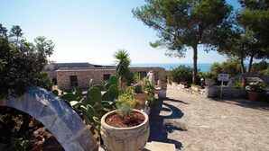 A stone building with a view of the sea, surrounded by potted plants and a stone archway. - Dada, Pool Residence (Gagliano del Capo)