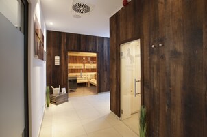 A reception area with a wooden wall, a reception desk, and a sauna visible through the door.