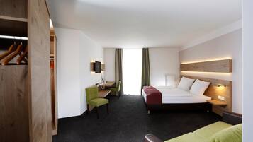 A hotel room with a bed, desk, chair, and wardrobe.