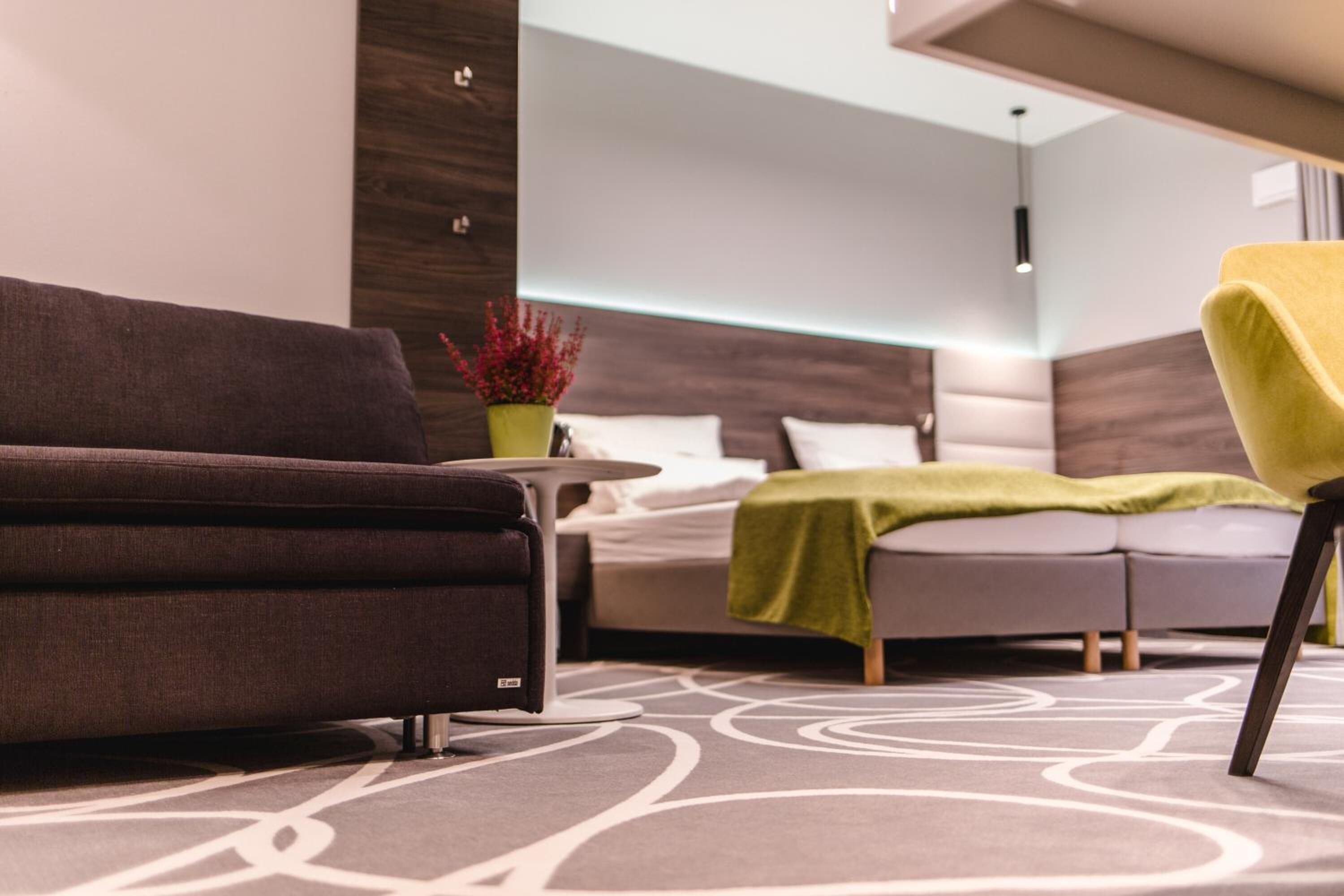 Une chambre d’hôtel moderne, équipée d’un canapé, d’une petite table et d’une plante verte.